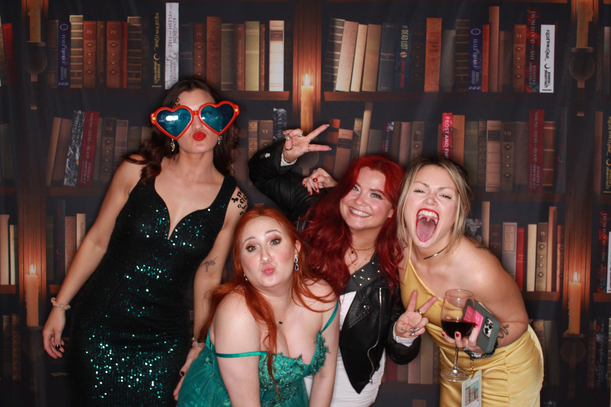 ApollyCon guests posing in front of the custom bookshelf backdrop